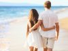 Vacation couple walking on beach together in love holding around