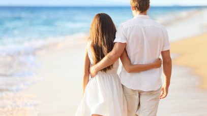 Vacation couple walking on beach together in love holding around